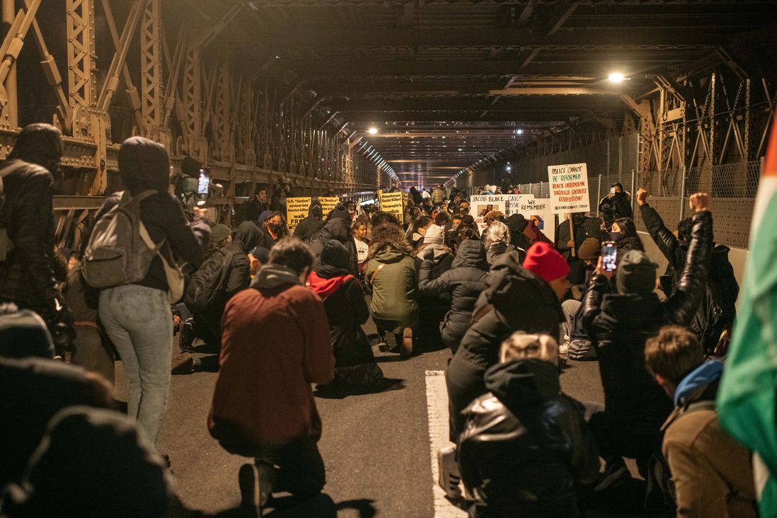 Scores of protesters on the Brooklyn Bridge take a knee during a demonstration against the not guilty verdict for Kyle Rittenhouse.